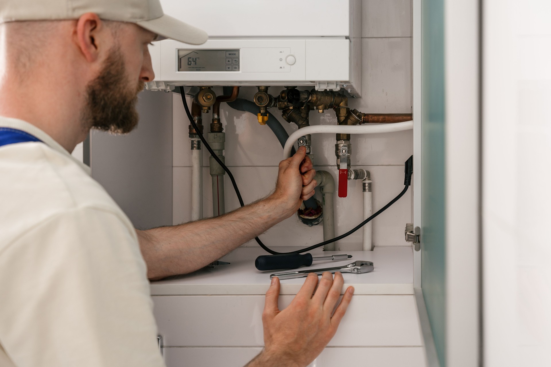 Repairman checking gas boiler for maintenance in residential bathroom setting